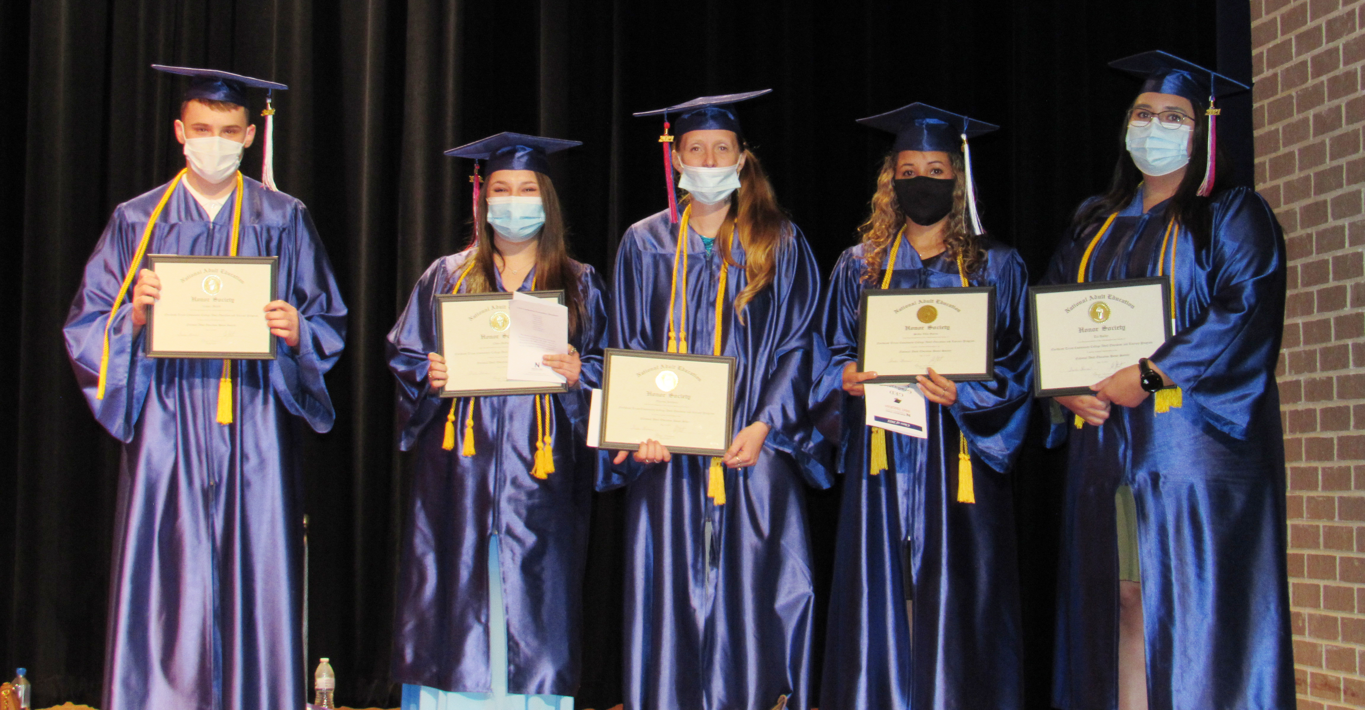 students on stage with their certificates