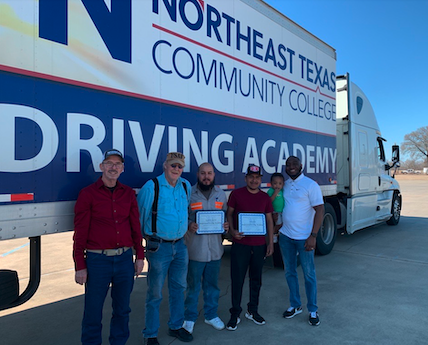 cdl graduates with instructors in front of truck. 