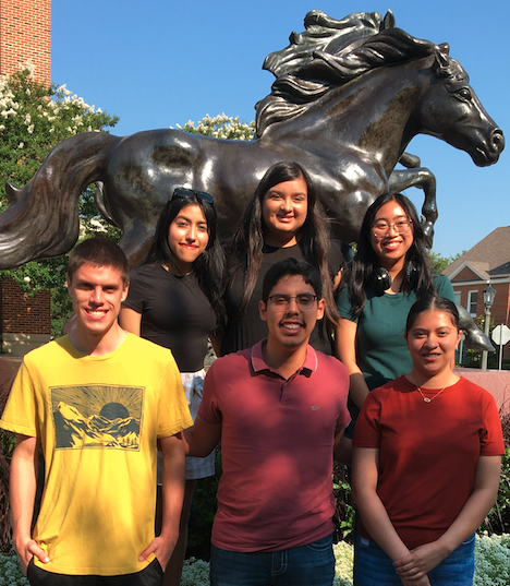 students in front of mustang statue
