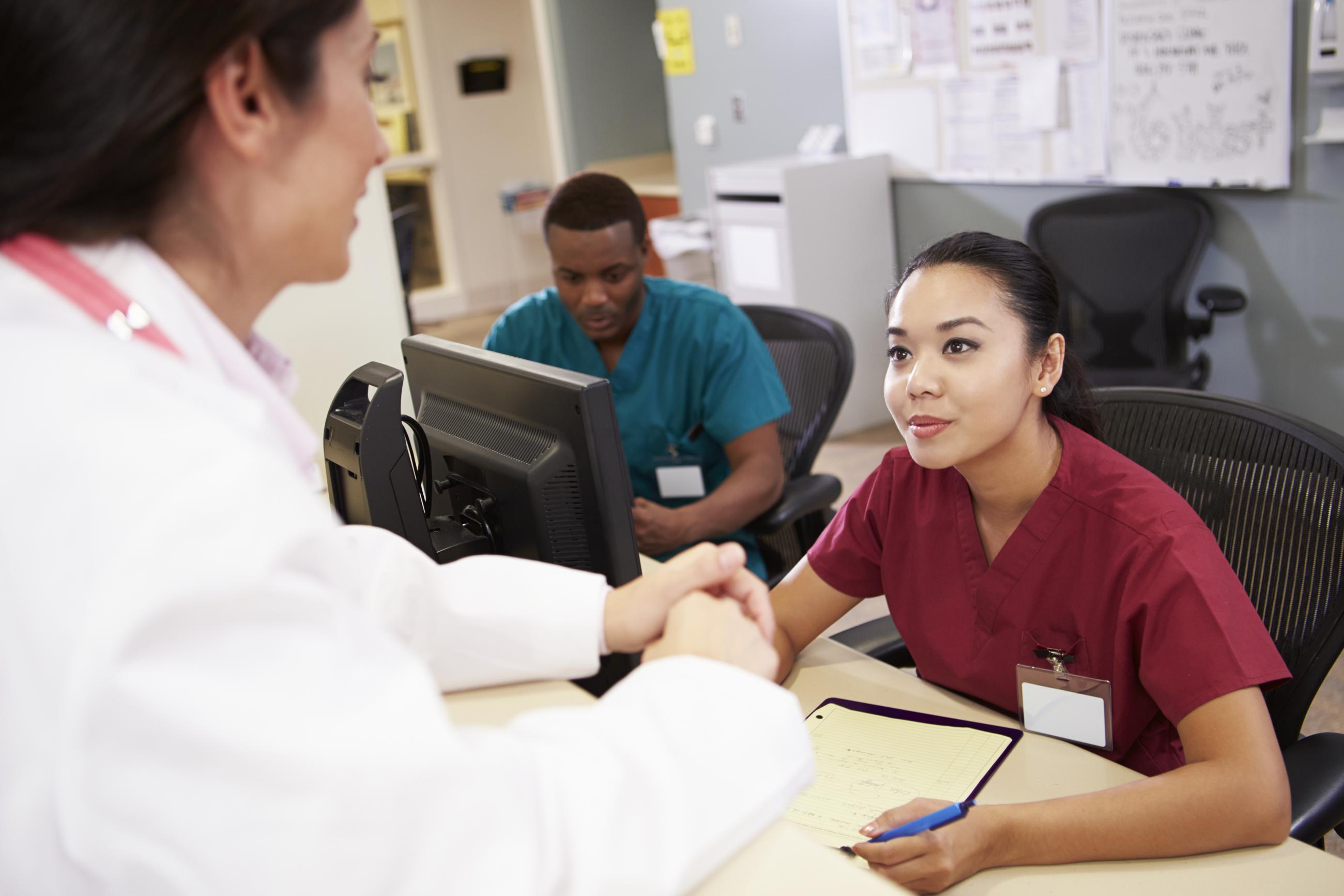 Medical assistant talking with doctor.