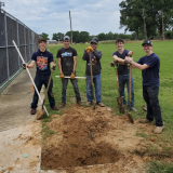 students standing next to big hole they dug