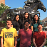 students in front of mustang statue